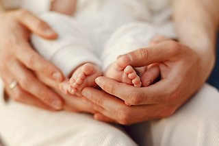 En förälder håller sina händer kring ett nyfött barns fötter.
