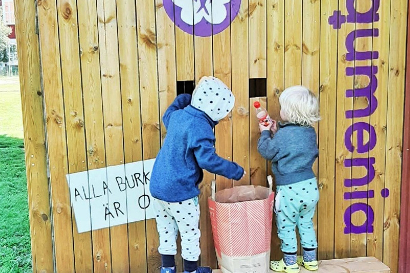 Två barn pantar flaskor i pantstation Equmenia