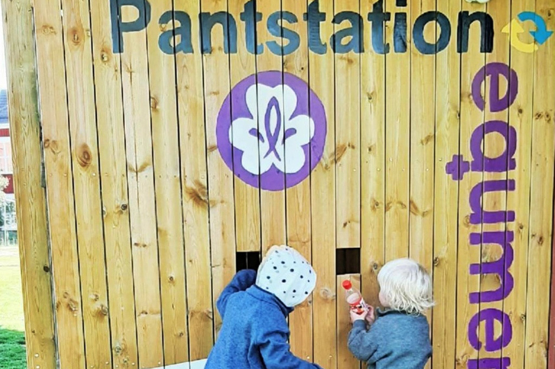 Två scouter pantar förpackningar i en egenbyggd pantstation.