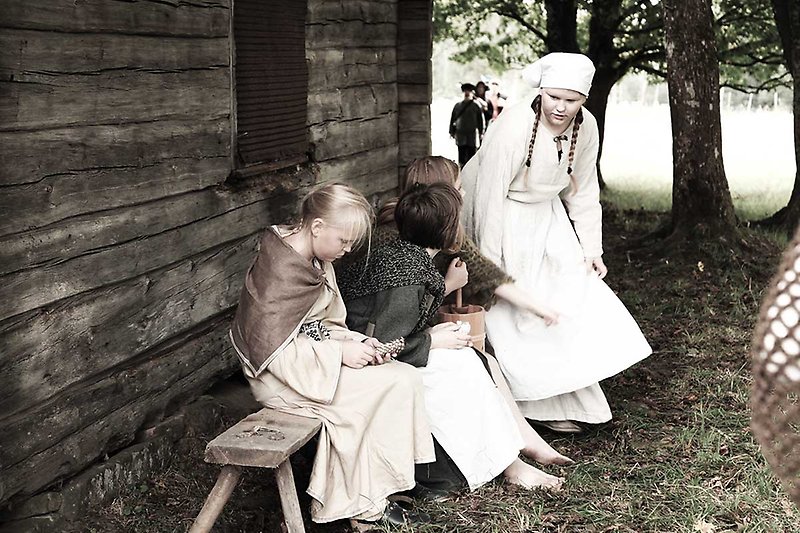 Barn på bänk i historiska kläder